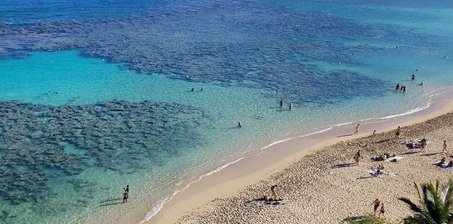 People snorkeling in the crystal clear waters of Hanauma Bay Nature Preserve with a volcanic crater in the background