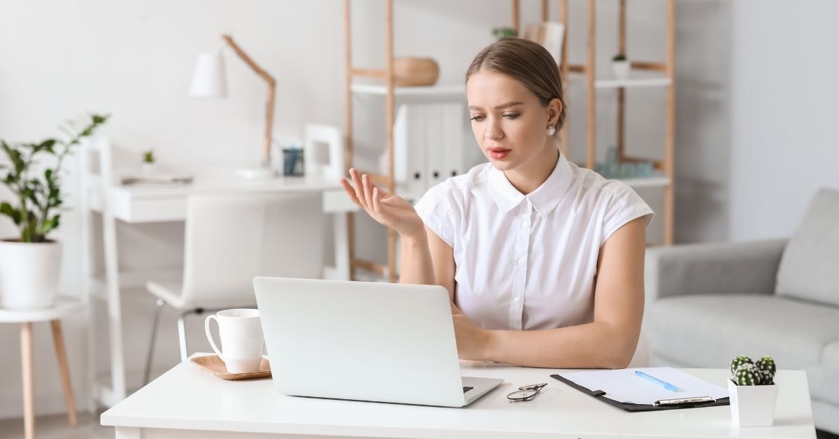 A concerned woman reviewing tax time information on her laptop at a home office desk.