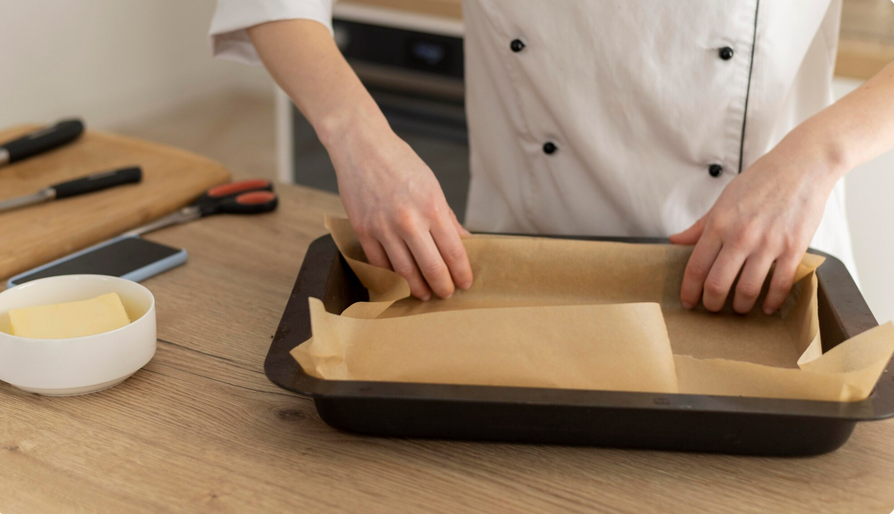 A chef preparing a baking sheet in a tray