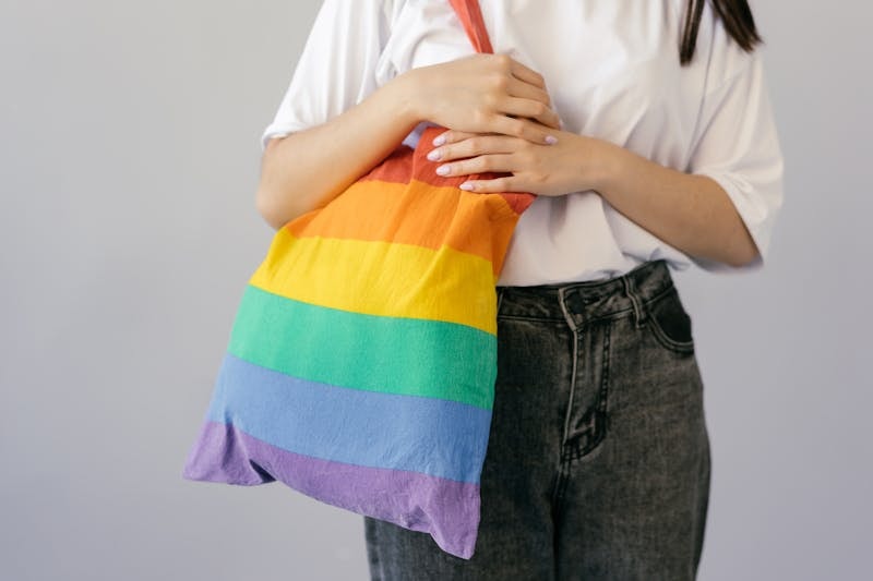 person holding rainbow colored tote bag