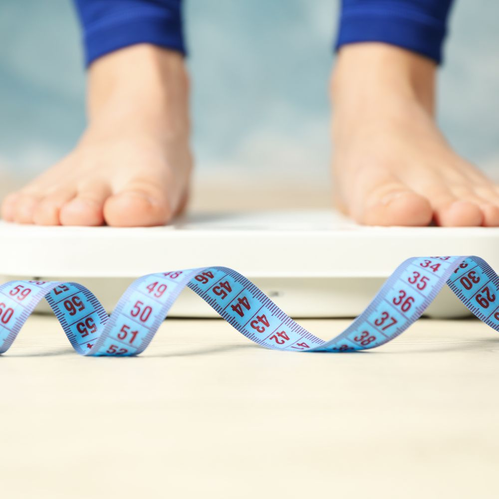 A person stepping on a weighing scale, representing the semaglutide weight loss effect in the treatment process and potential side effects.