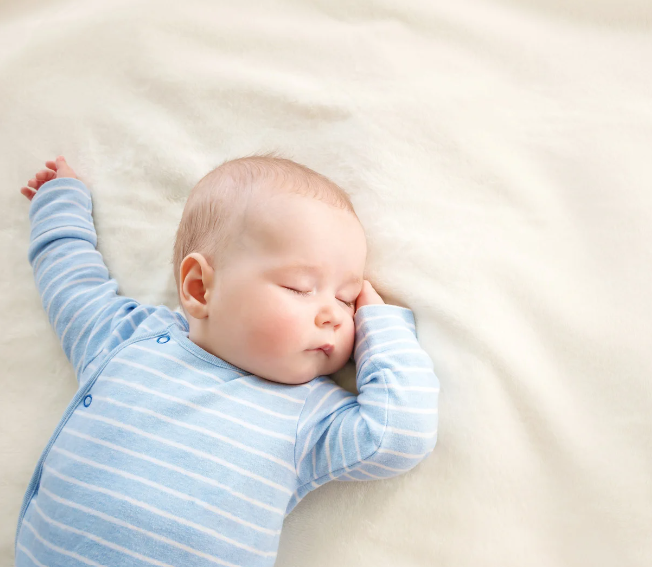 baby lying on their back in blue and white sleepsuit