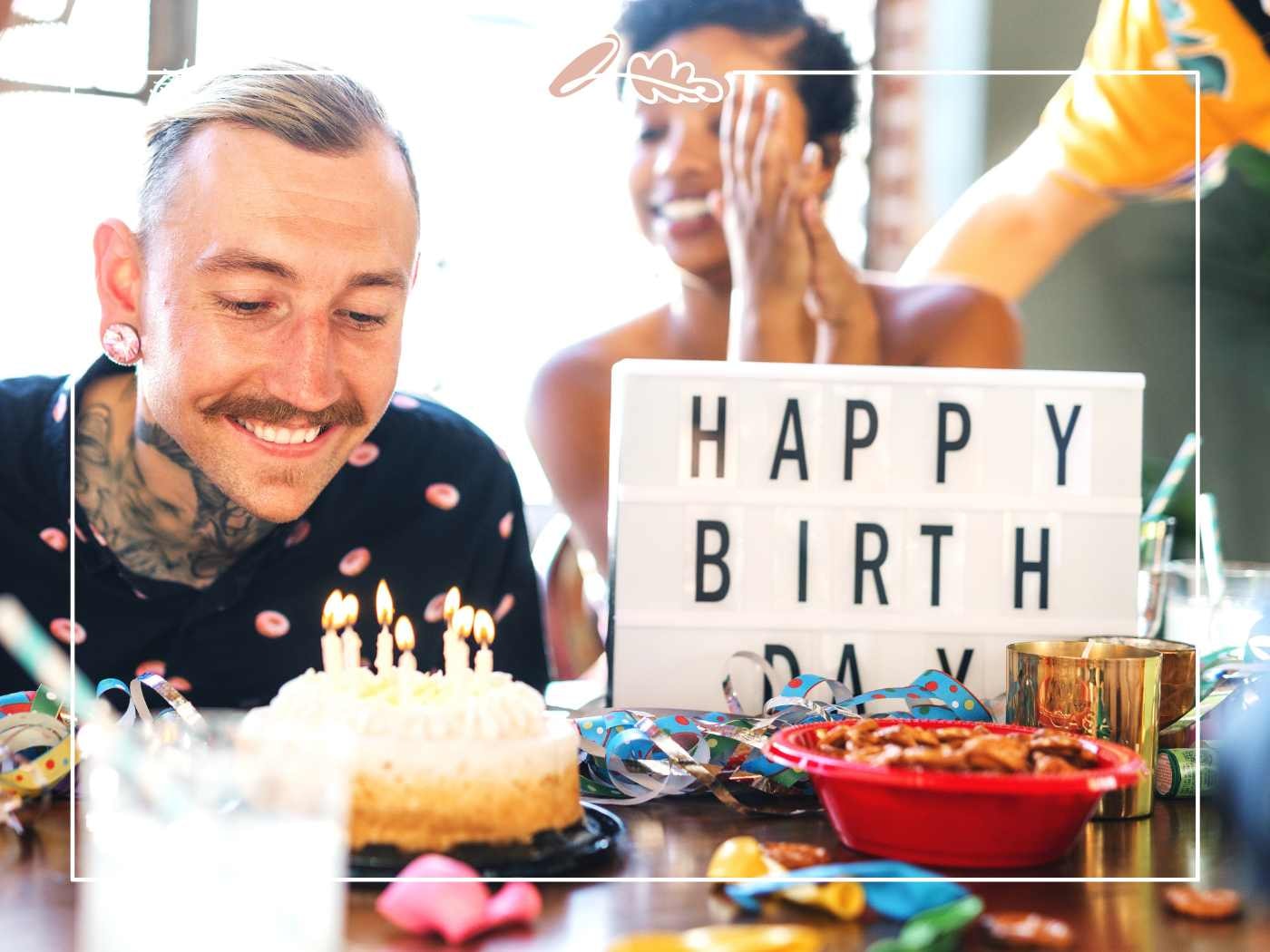 Birthday Wish for Boyfriend – man smiling at birthday cake and candles beside a “Happy Birthday” lightbox at a party table