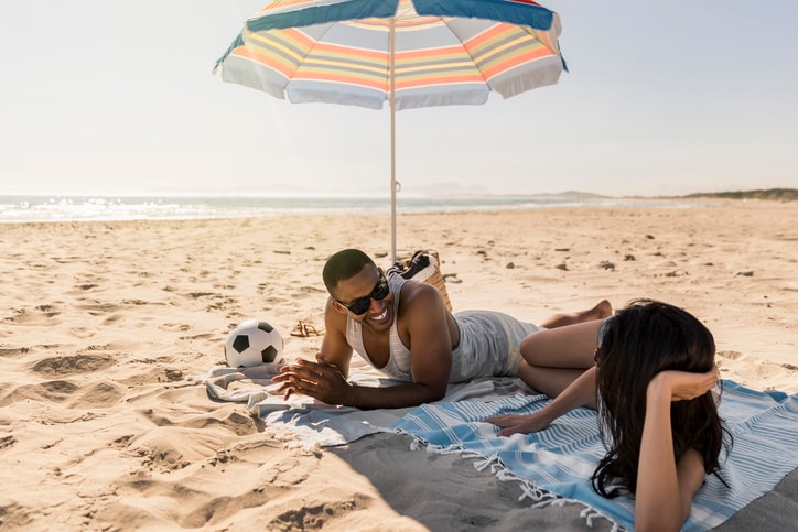 Happy couple under a beach umbrella. 