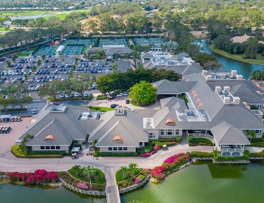 A panoramic view captures a luxurious golf course at sunset, showcasing shimmering water features and elegant homes lining the fairway, embodying the resort-style living of Grey Oaks Naples. This scene highlights the beauty and tranquility of this prestigious community, known for its championship golf courses and exceptional lifestyle.