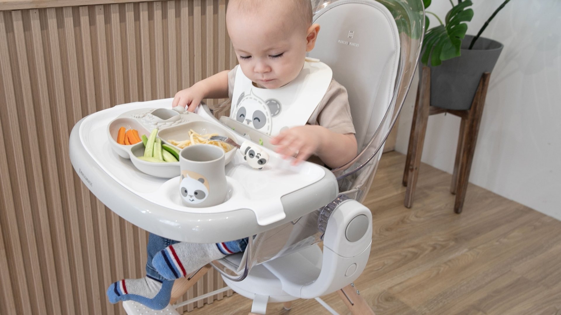 A baby is sitting upright in a high chair, eagerly prepared for their first solid foods, showcasing a joyful expression. This moment marks the beginning of baby led weaning, where the baby can explore a variety of age-appropriate finger foods, such as steamed sweet potatoes and soft fruits, while developing fine motor skills and self-feeding abilities.
