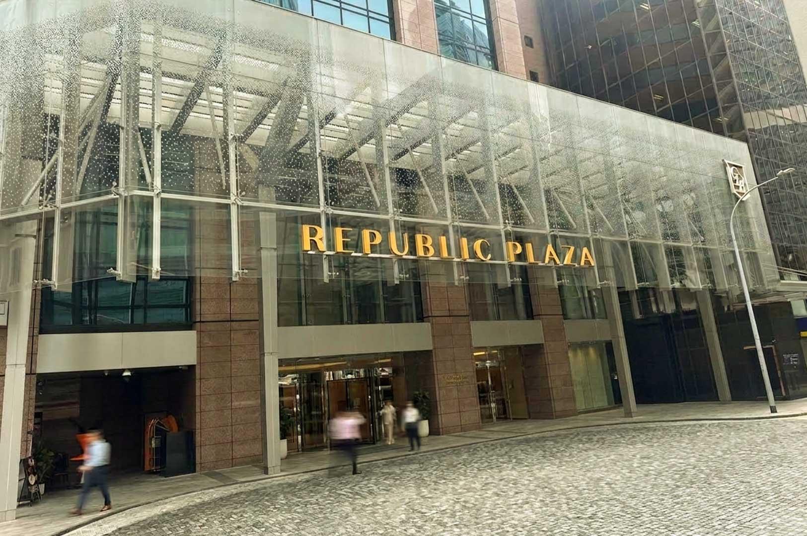 Street-level view of the Republic Plaza building entrance in Singapore featuring gold lettering under a glass canopy.
