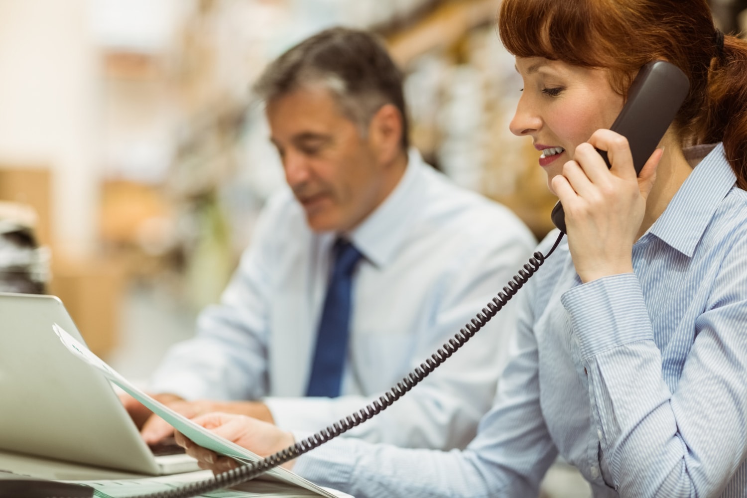 Team members use simple business phone systems in a fast-paced office environment, illustrating easy-to-use and affordable business communication solutions.
