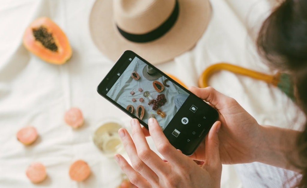 Person holding a smartphone taking a photo of items on a flat surface