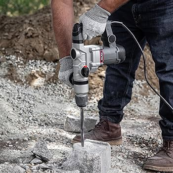 A person drilling a hole in asphalt with a rotary hammer drill bit