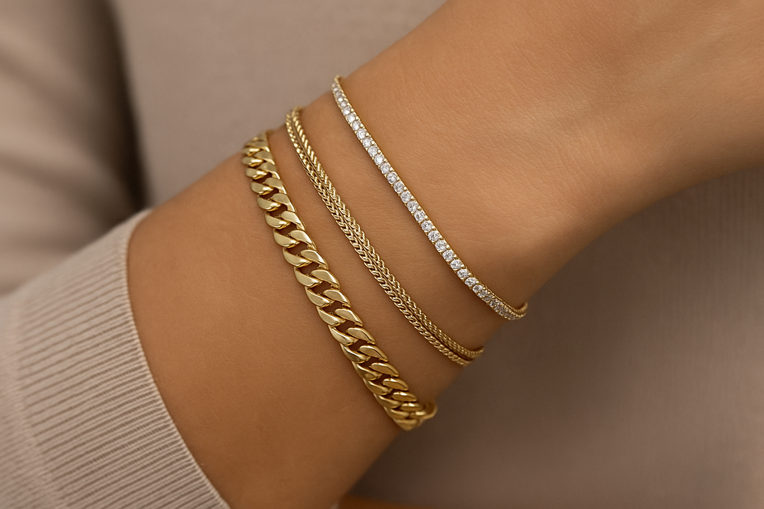 Ant moters riešo skirtingo pločio ir svorio auksinės apyrankės