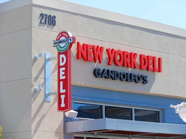 Daytime view of Gandolfo’s New York Deli in Oxnard featuring halo-lit channel letters and a classic blade sign, combining visibility and character for a standout storefront.