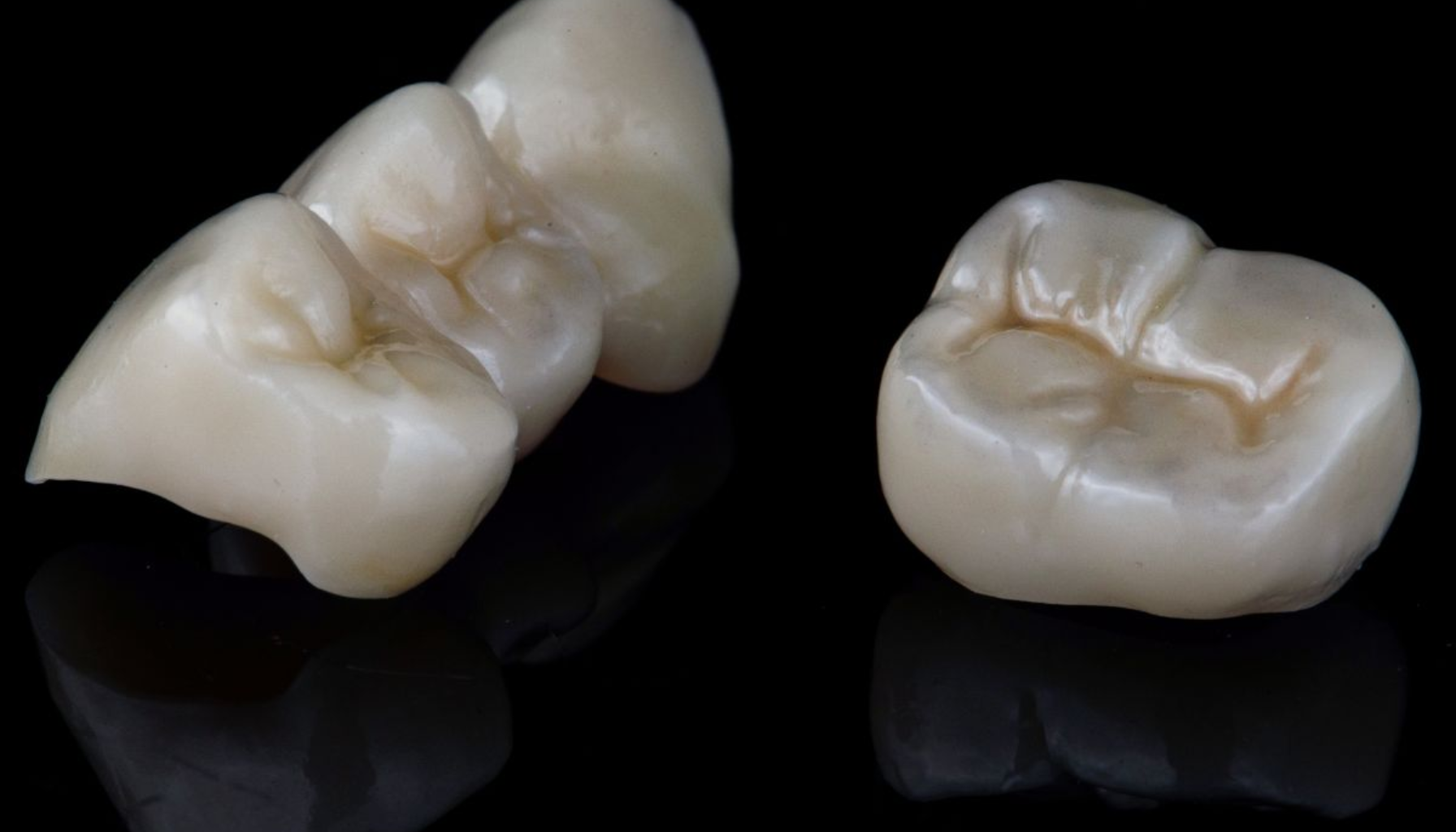 To keramiske tannkroner på svart bakgrunn, viser detaljer i overflaten for dental restaurering.