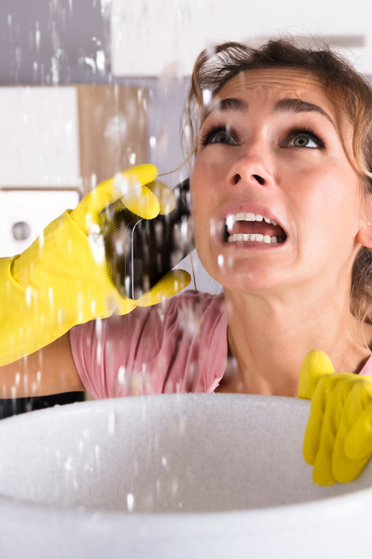 Frau in Panik mit einem Wasserschaden in der Küche ruft Installateur an
