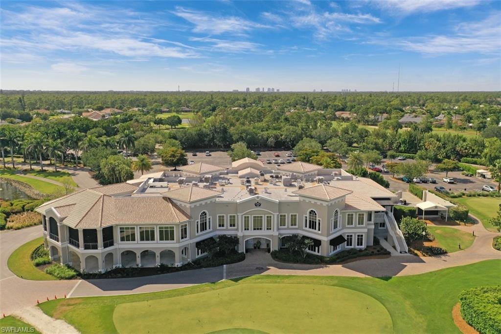 An aerial view of Imperial Golf Estates in Naples, FL, showcases its rolling hills, serene spring-fed lakes, and tree-lined streets that wind through the gated community, offering breathtaking views for residents and golf enthusiasts alike. The image captures the essence of this peaceful neighborhood, highlighting its beautiful homes and the inviting landscape of the golf club.