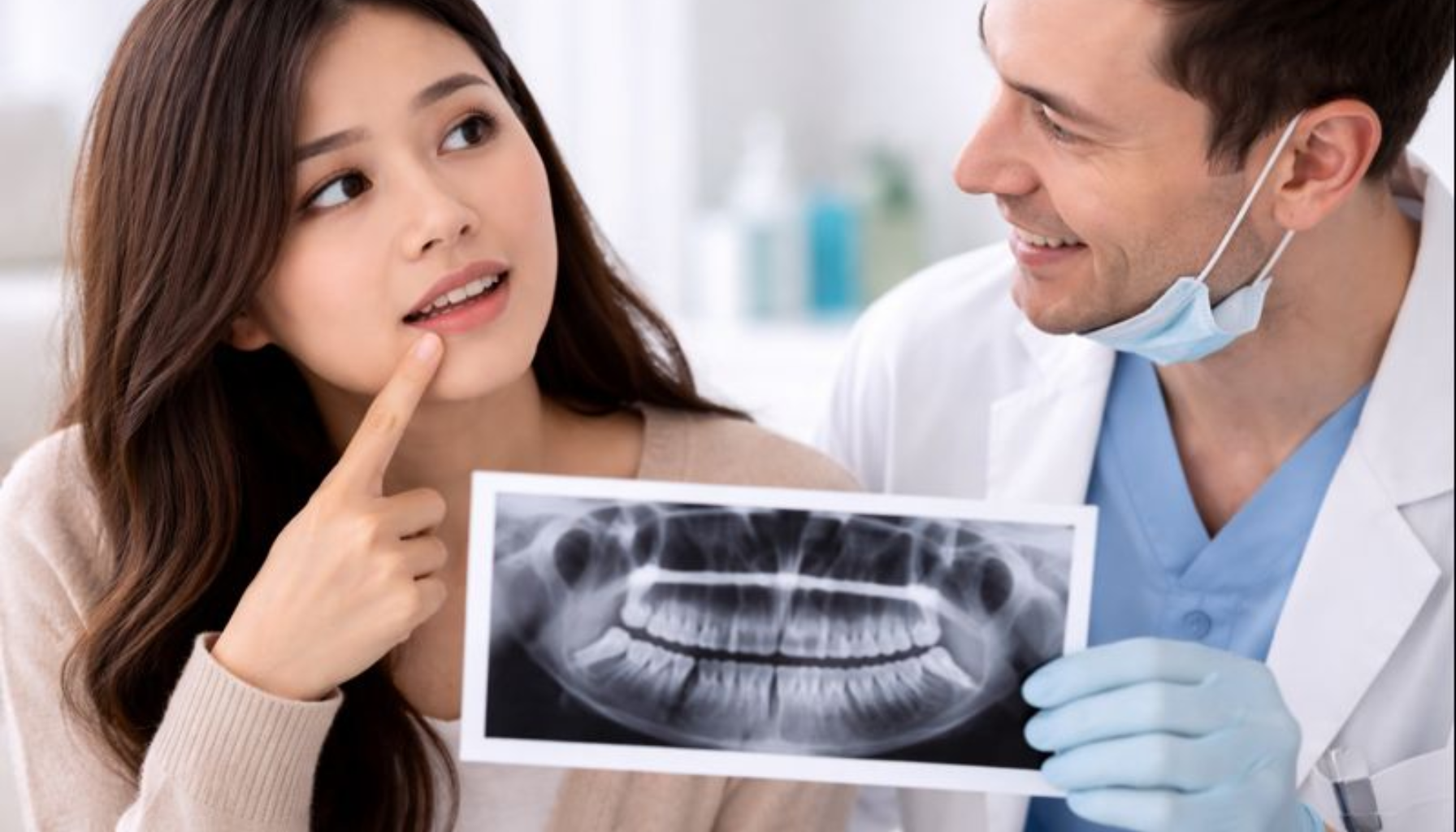 Får Alle Visdomstenner? Myten og Fakta om Tredje Jeksel 15 Kvinne peker på visdomstann mens tannlege viser røntgenbilde og forklarer tennenes utvikling i munnen.