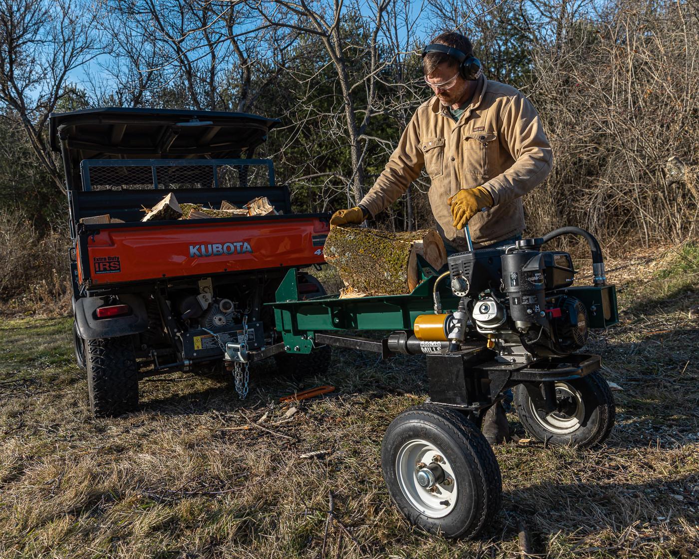 A man pulling a log onto the bed of his Woodland Mills LS218 Log Splitter. 