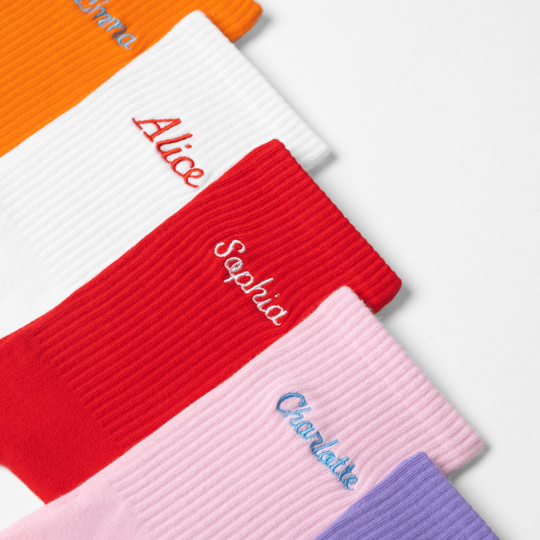 A collection of women's customised crew socks with female names embroidered onto each pair.