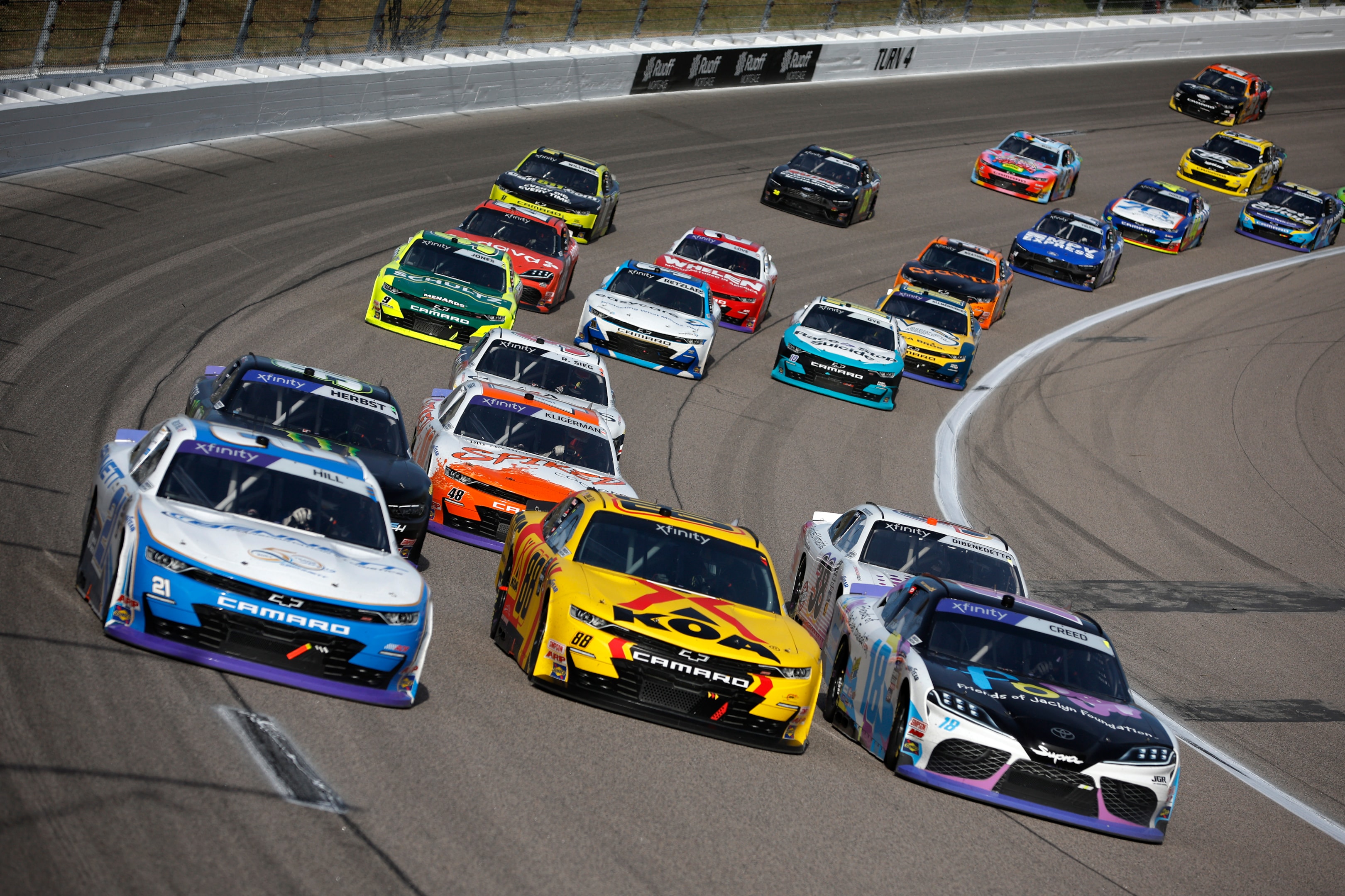 Austin Hill, driver of the Bennett Transportation Chevrolet, Connor Zilisch, driver of the KOA/RTIC Chevrolet and Sheldon Creed, driver of the Friends of Jaclyn Foundation Toyota, race during the NASCAR Xfinity Series Kansas Lottery 300 at Kansas Speedway on September 28, 2024 in Kansas City, Kansas. 