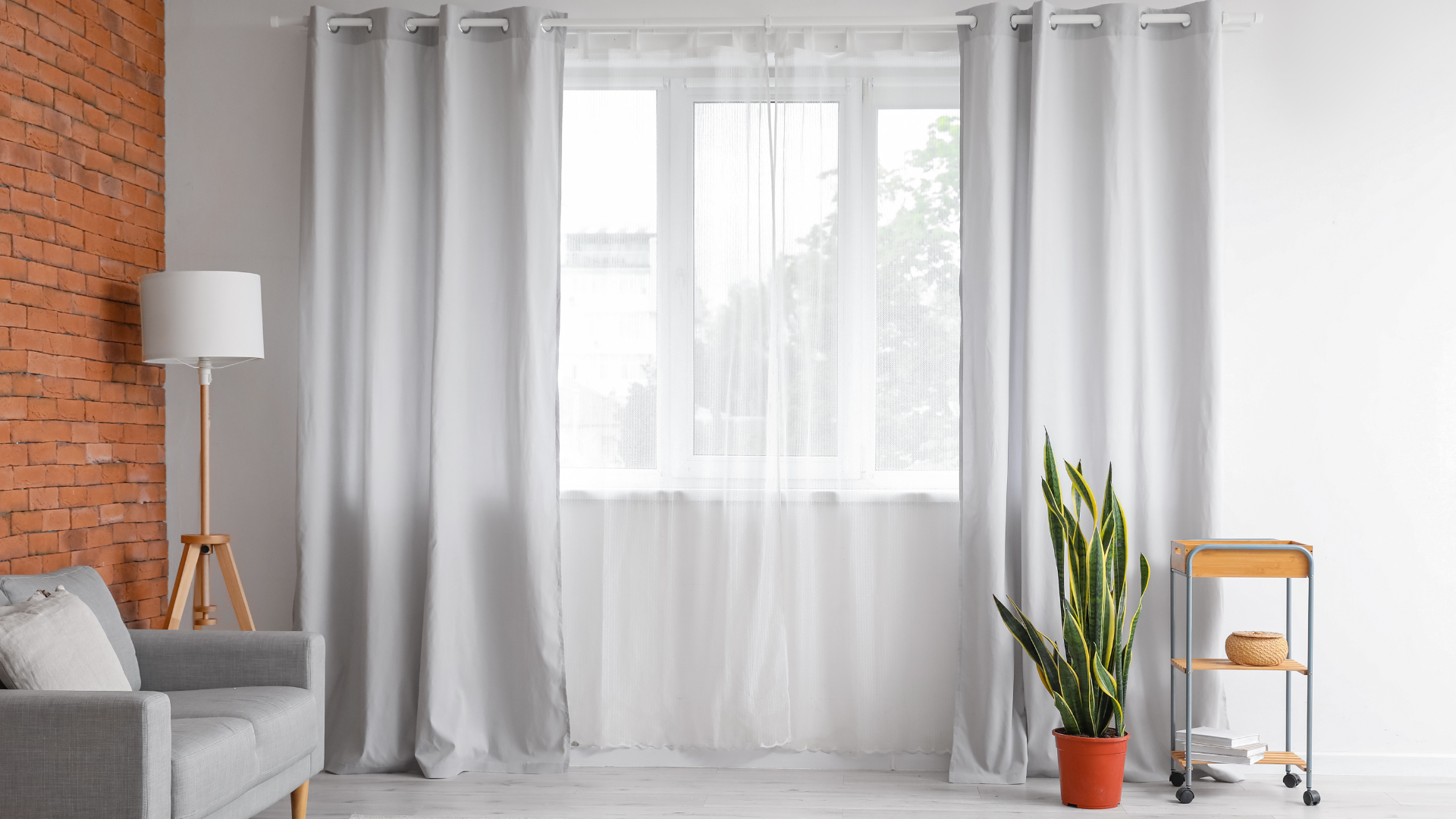 Light grey floor length curtains on a white pole in modern room decor