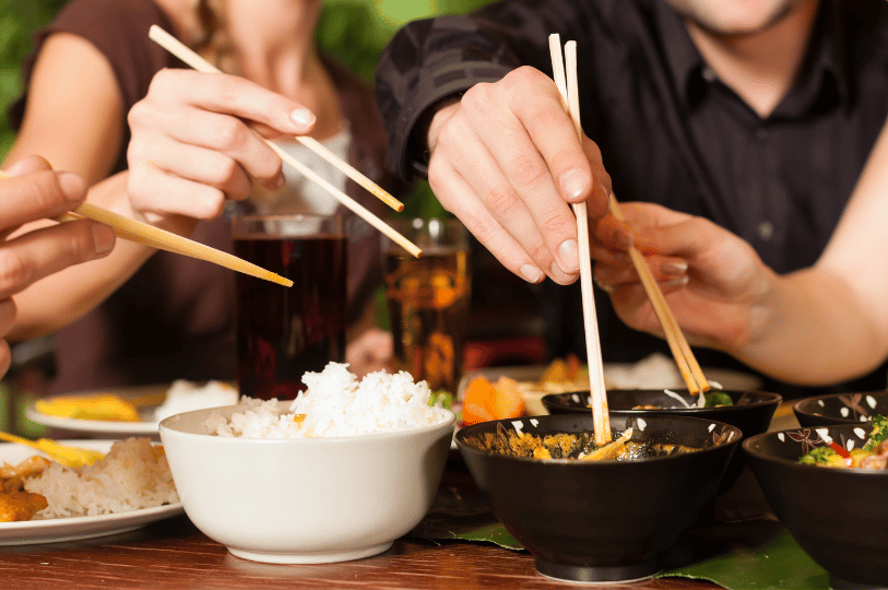 A group of people using chopsticks to enjoy a meal at a restaurant, illustrating the dining experience that Singapore restaurant owners aim to promote through effective SEO.