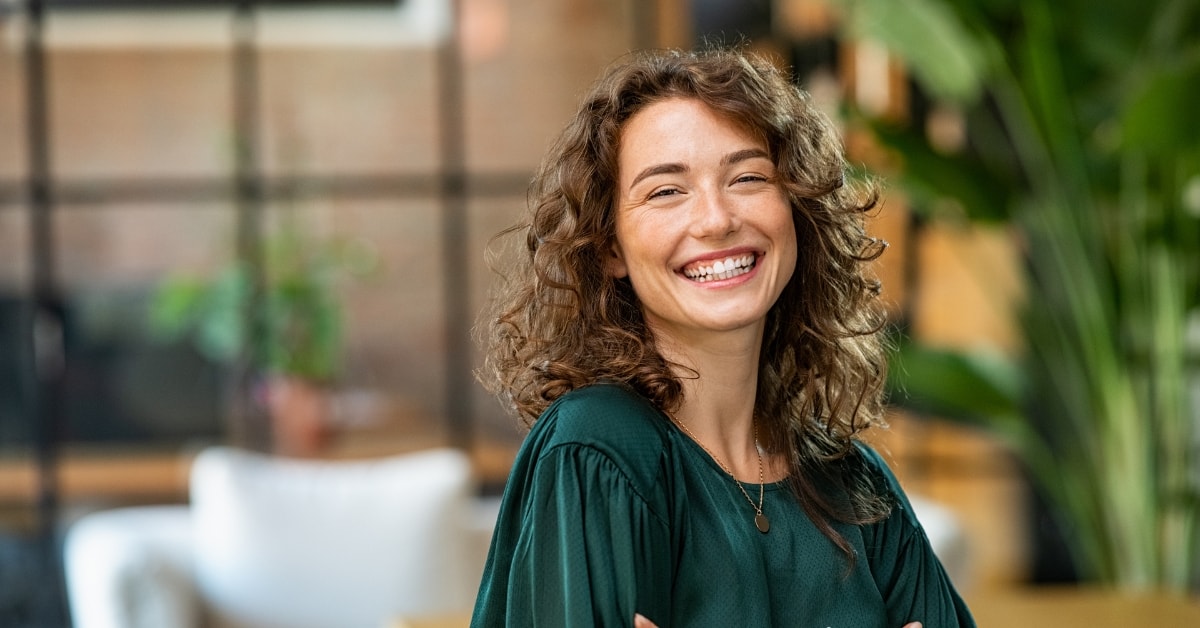 Happy woman in a green blouse, showing satisfaction after managing OnlyFans seasonal tax duties.