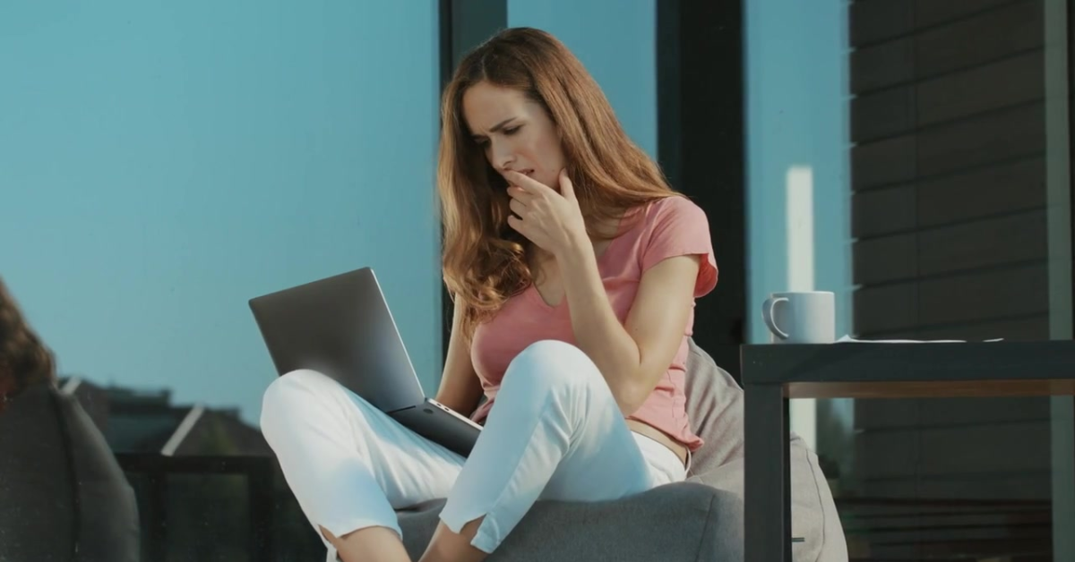 A woman sitting on a balcony, thoughtfully calculating the 1099 tax percentage for her earnings.