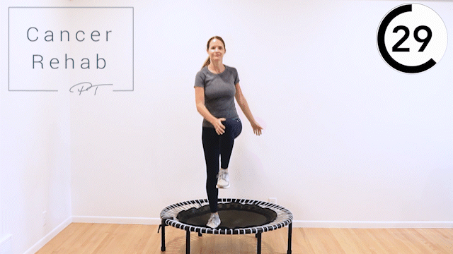 A woman tapping her hand to the opposite knee on a mini trampoline.