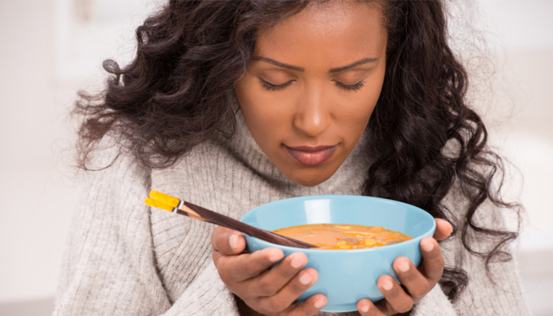 Mistet Smak og Luktesans: Hvordan Det Påvirker Munnhelsen 11 Kvinne holder en bolle med varm suppe og lukter forsiktig før hun spiser.