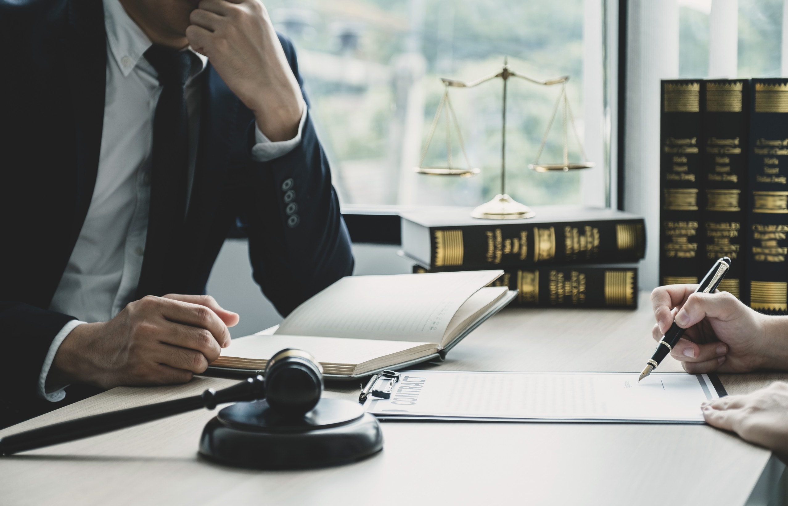 A workplace accident solicitor sitting behind a desk and talking to a client about broken bone at work compensation.