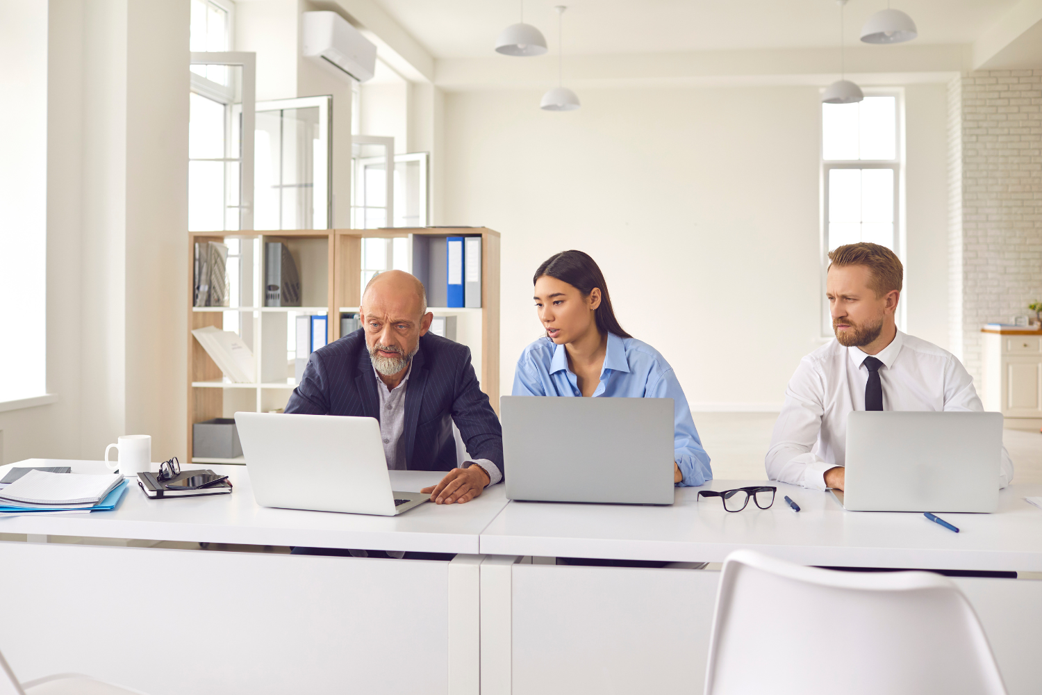 Three professionals, analyzing broker submissions and loan documents.