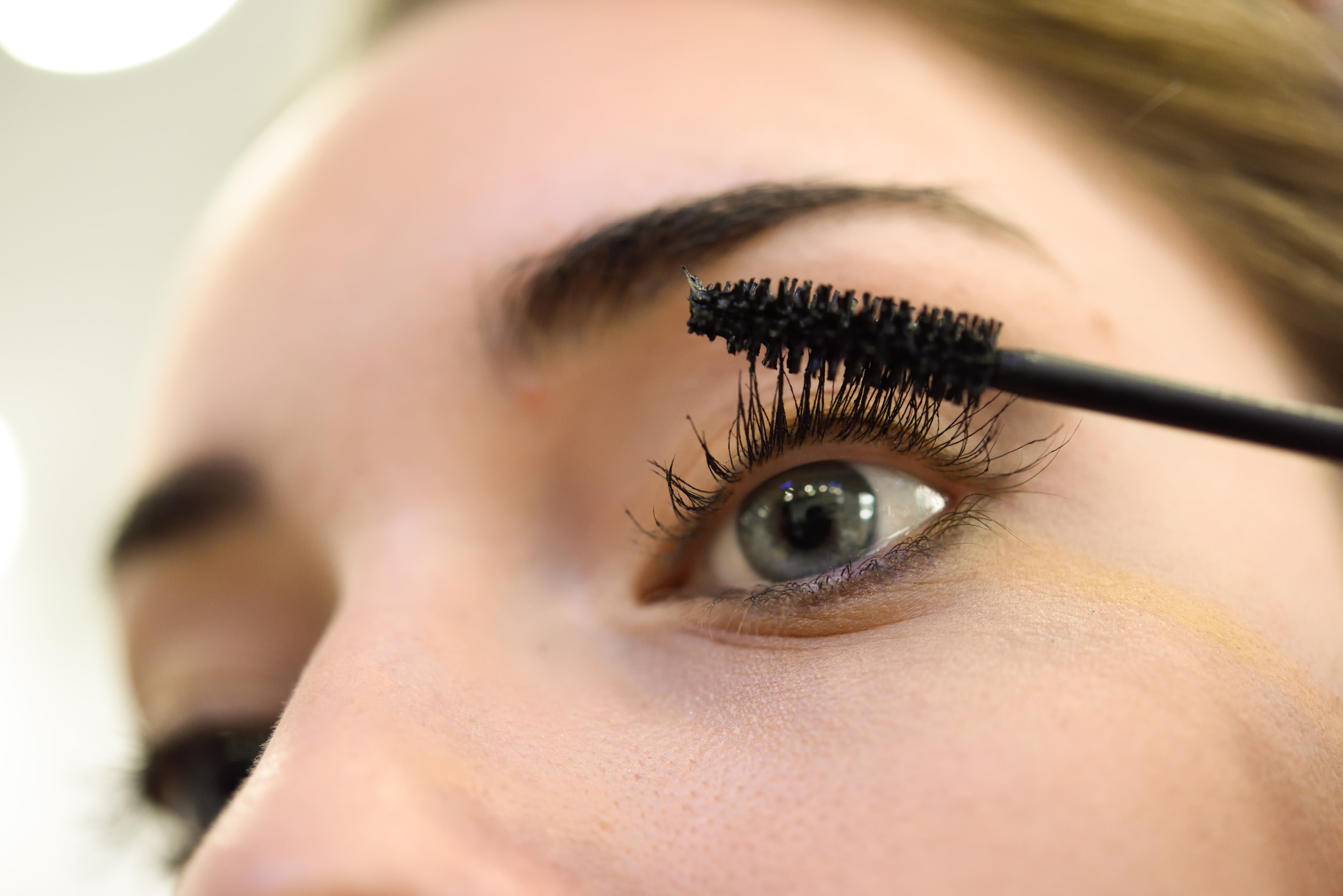 a woman applying mascara to her eyelashes