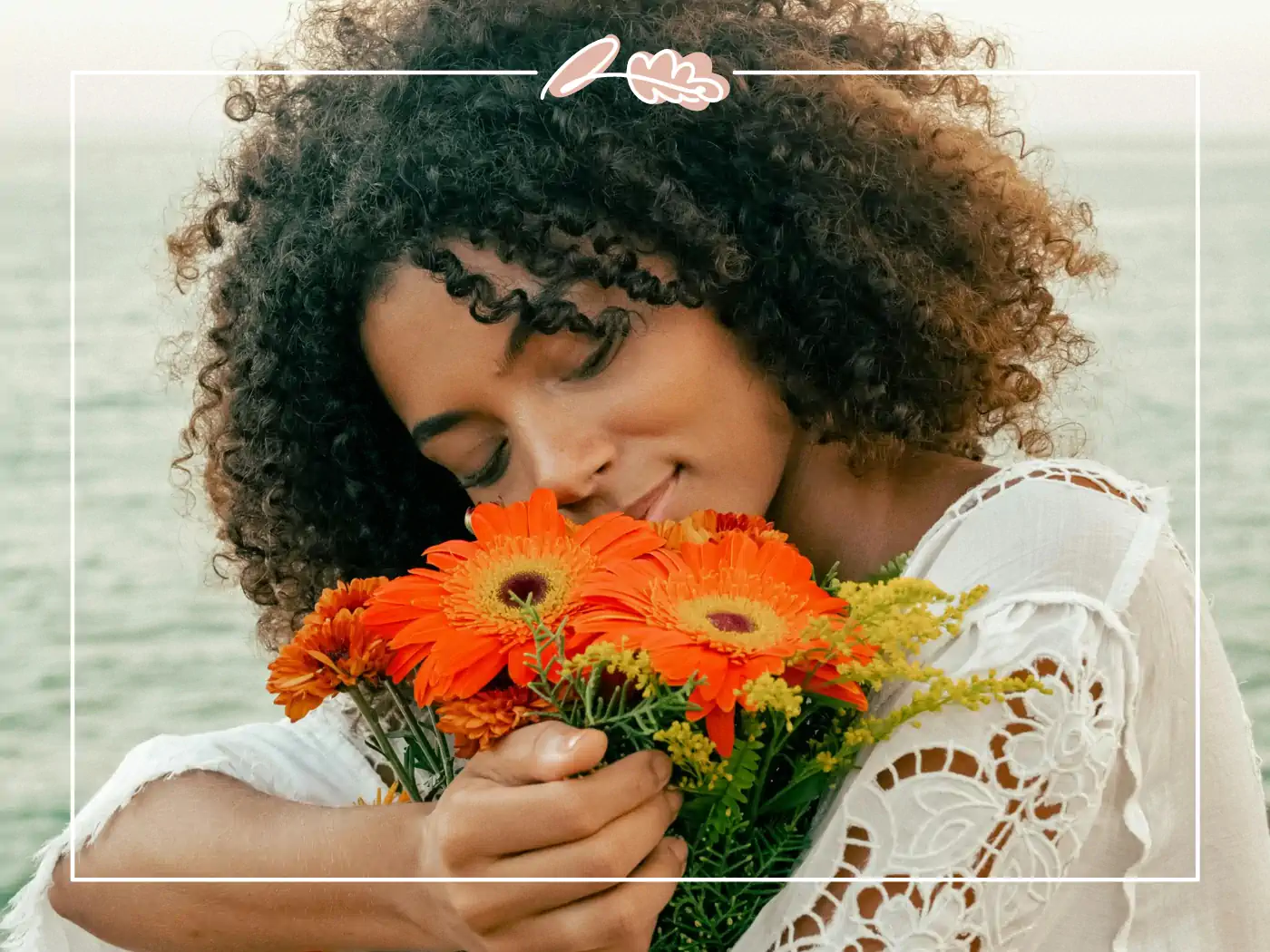 Woman with curly hair embracing a bouquet of orange flowers - Fabulous Flowers and Gifts