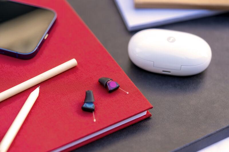 The image features modern, small, and discreet hearing aids highlighting their design for individuals experiencing various types of hearing loss, including conductive and sensorineural hearing loss. These devices are essential for enhancing hearing ability and improving communication for those with varying degrees of hearing loss.