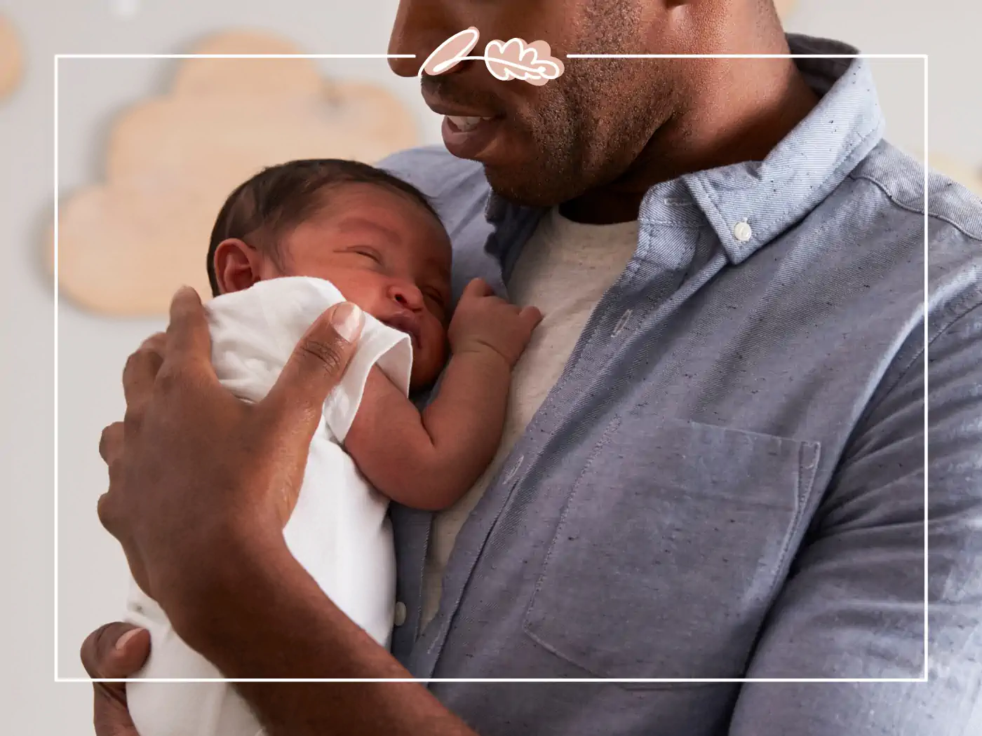 A father hokding his new born baby in a nursery with clo9uds in the background. Fabulous Flowers and Gifts