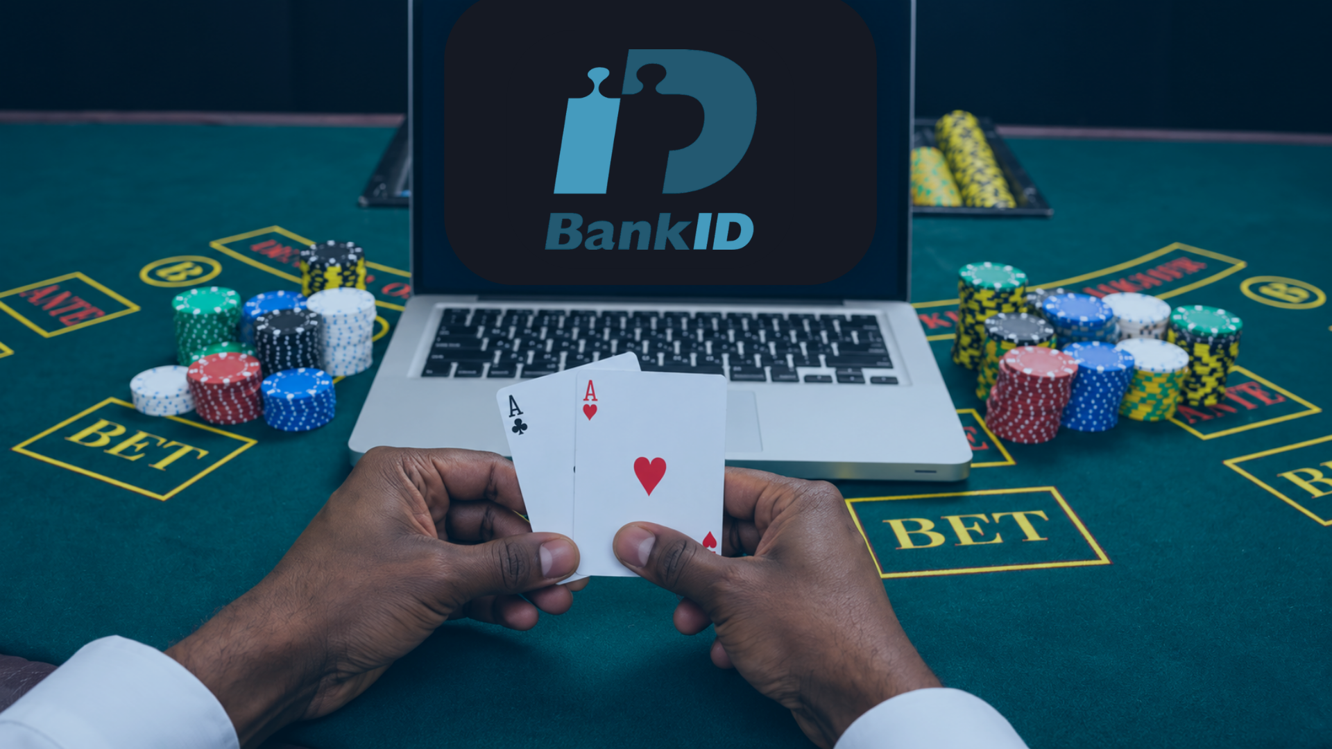 Händer håller två ess framför en laptop med BankID på skärmen och casinochips på bordet