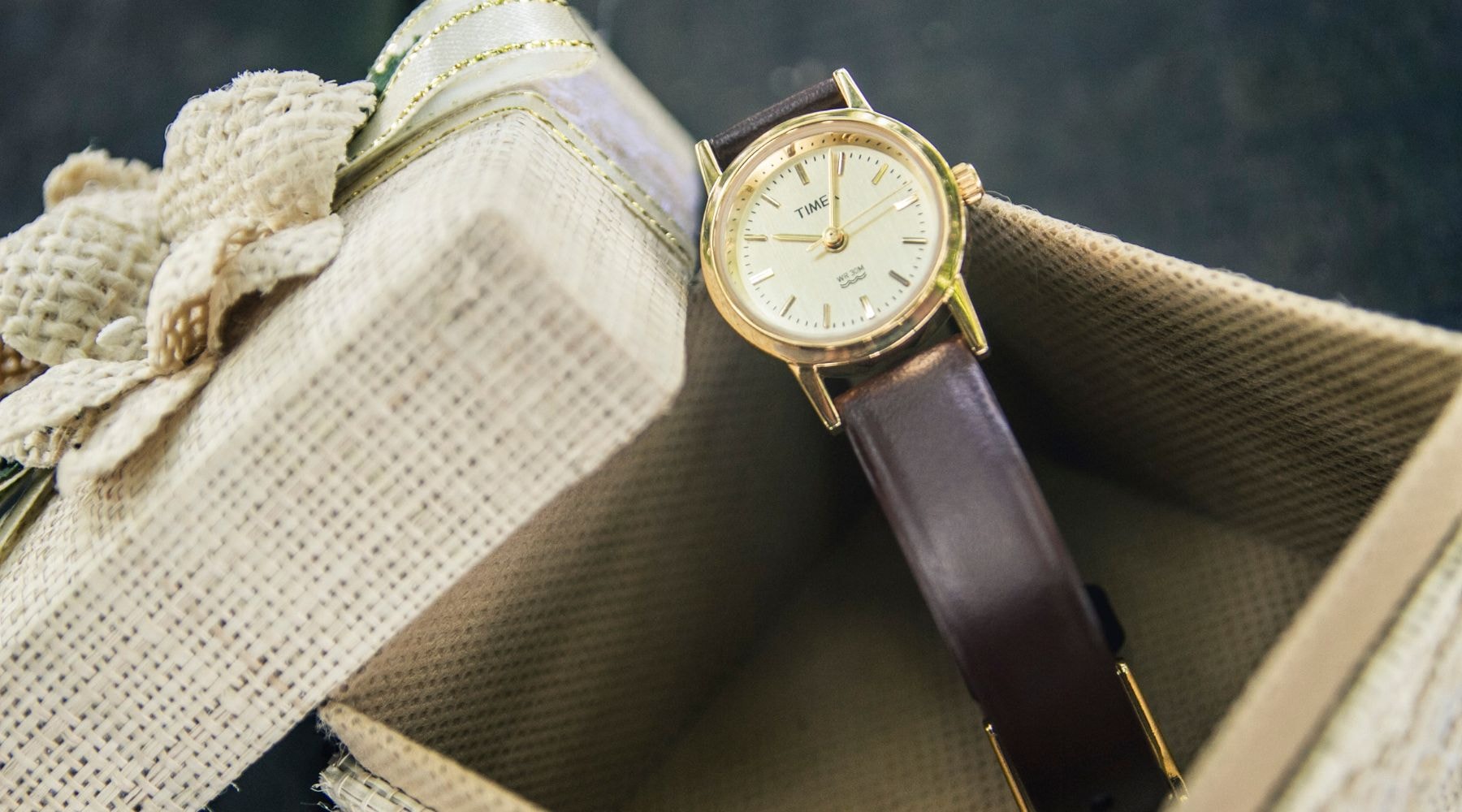 Classic wristwatch presented in a natural textured gift box with a white ribbon, symbolizing timeless elegance.