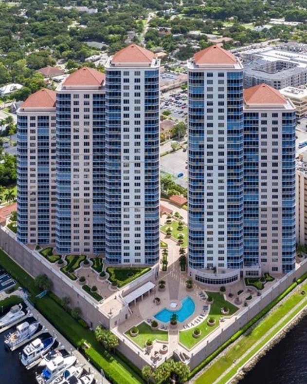 The image depicts a luxury pool deck with stylish cabanas, offering breathtaking views of the Caloosahatchee River in downtown Fort Myers. This urban waterfront setting features a heated pool and resort-style amenities, creating a perfect spot for relaxation and enjoyment in the prestigious High Point Place.