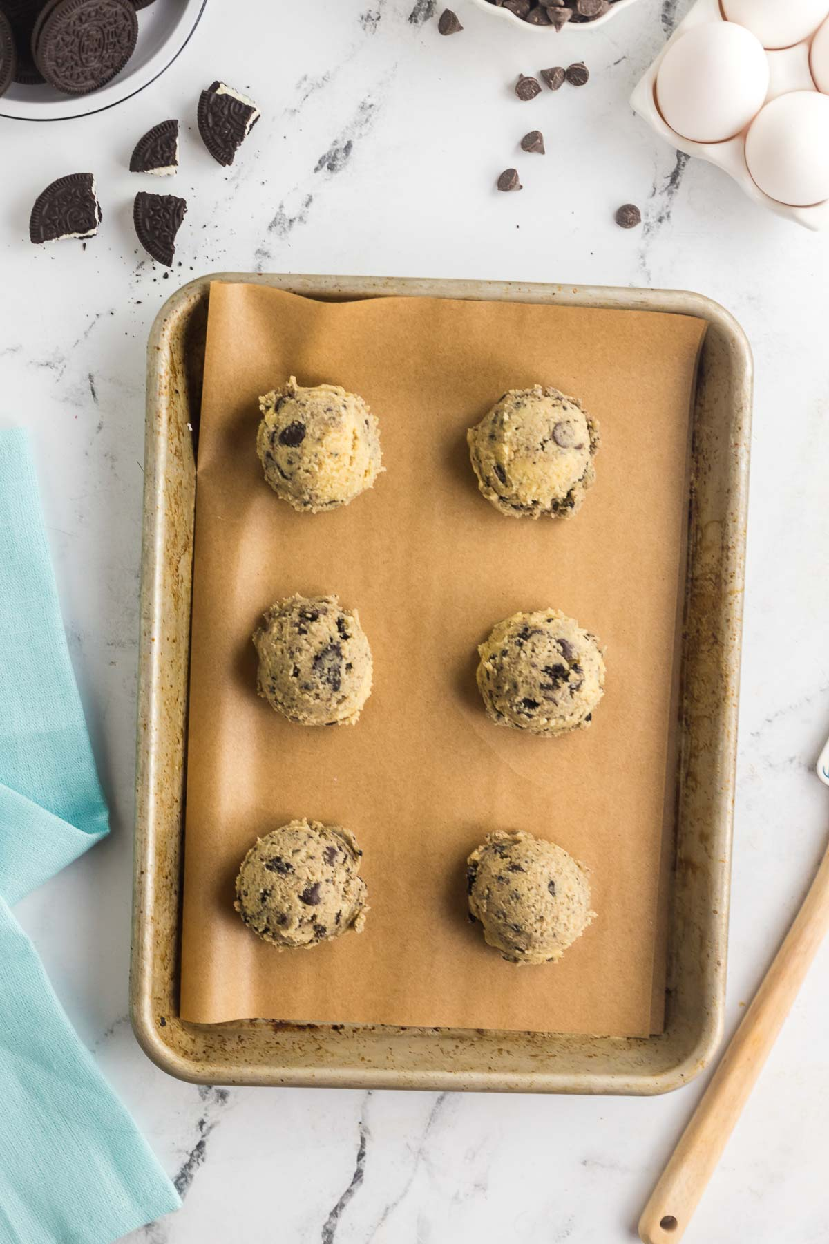 six oreo cheesecake cookie balls on parchment lined baking sheet