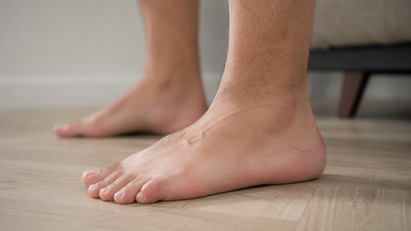 Bare feet standing on a hardwood floor, showing the arch and heel