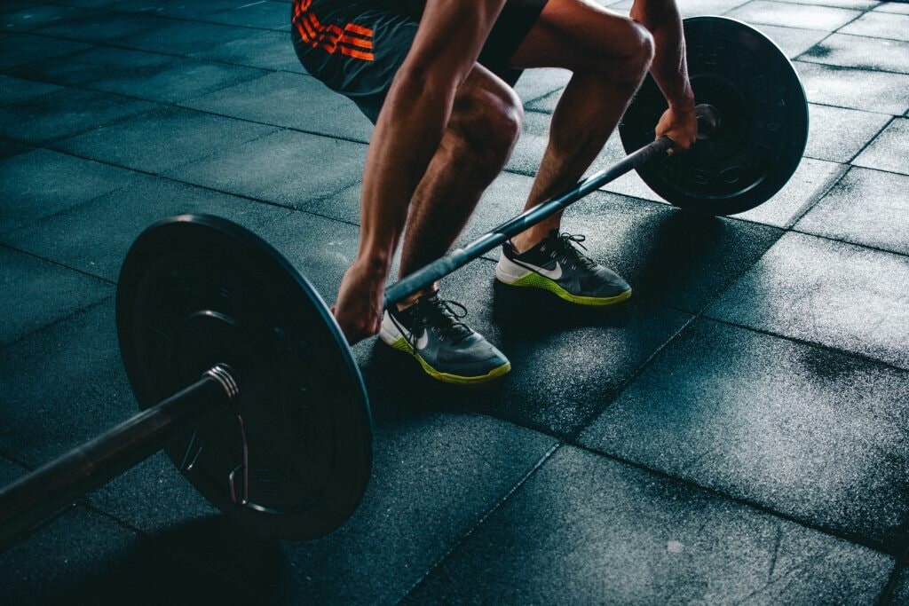 Athlete setting up for a barbell lift on a gym floor.