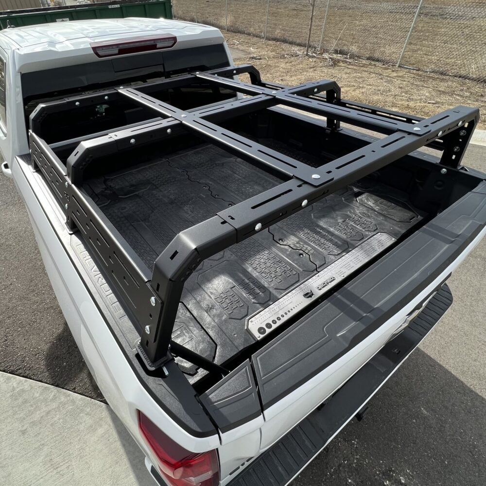 A low profile aluminum overland rack mounted on a Toyota Tacoma truck bed