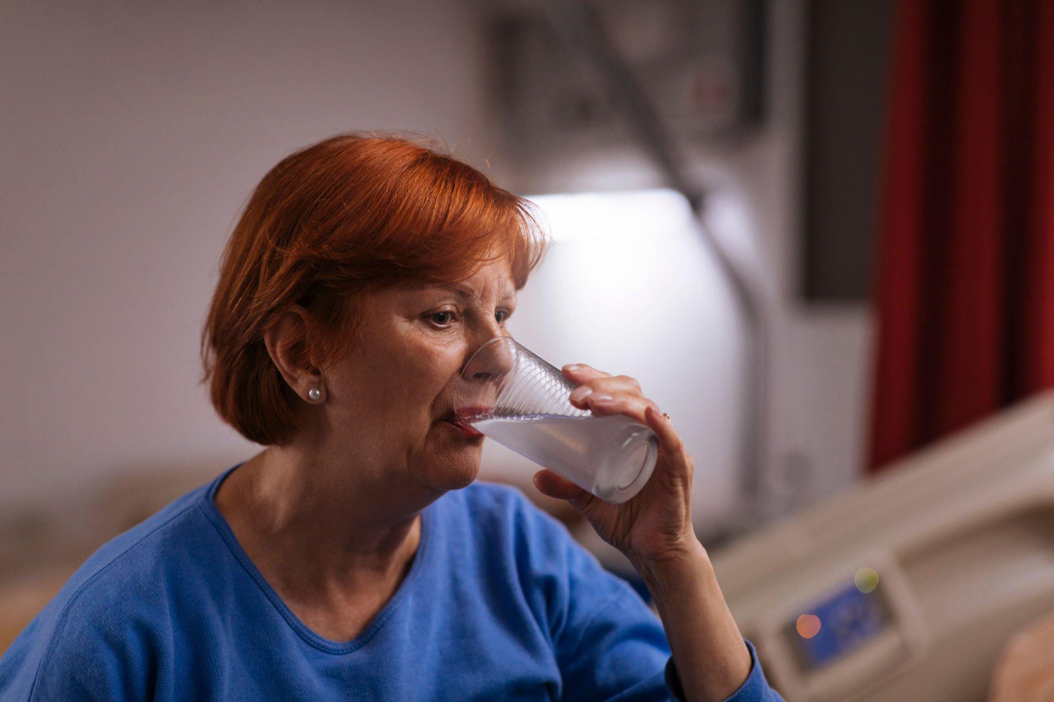 A person drinking a liquid as part of an Oral Glucose Tolerance Test (OGTT), blood tests for glucose tolerance. Glucose screening test