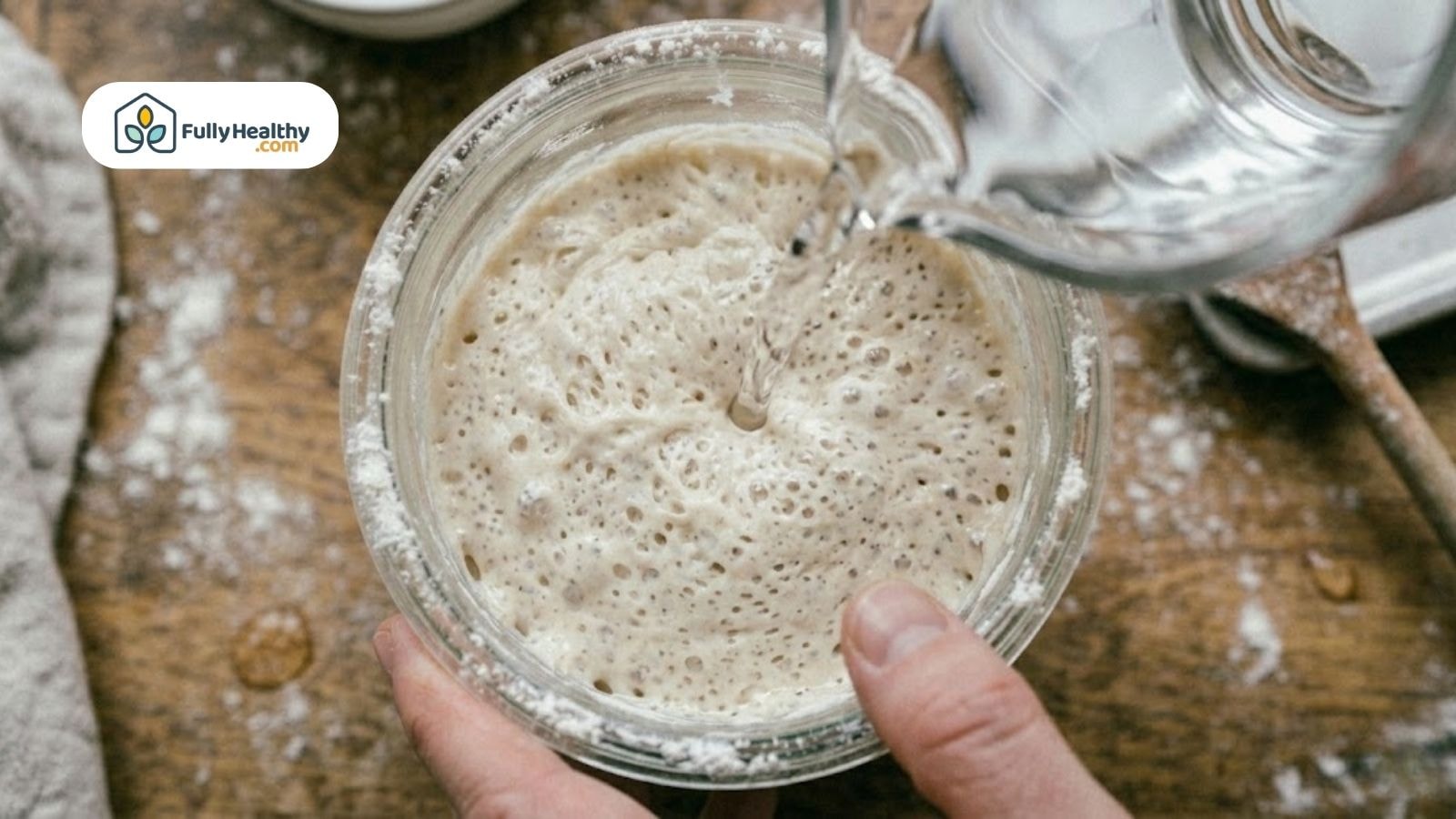 Pouring water into bubbly sourdough starter in a jar.