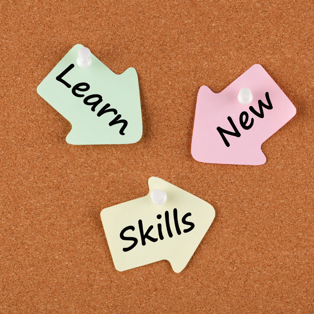 cork board with paper arrows on saying learn, new, and skills