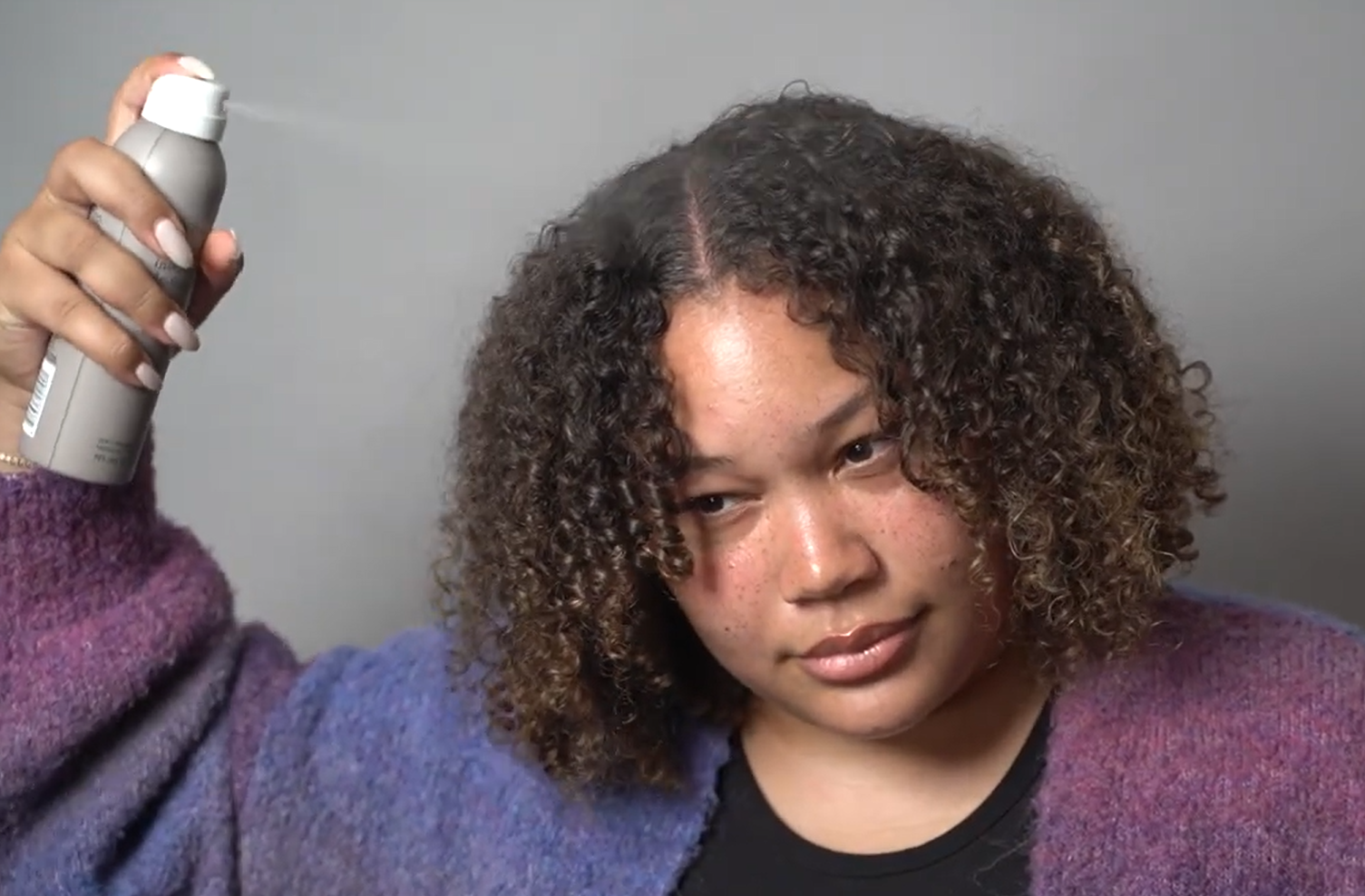 spraying Living Proof No Frizz de frizzer on frizz prone hair types