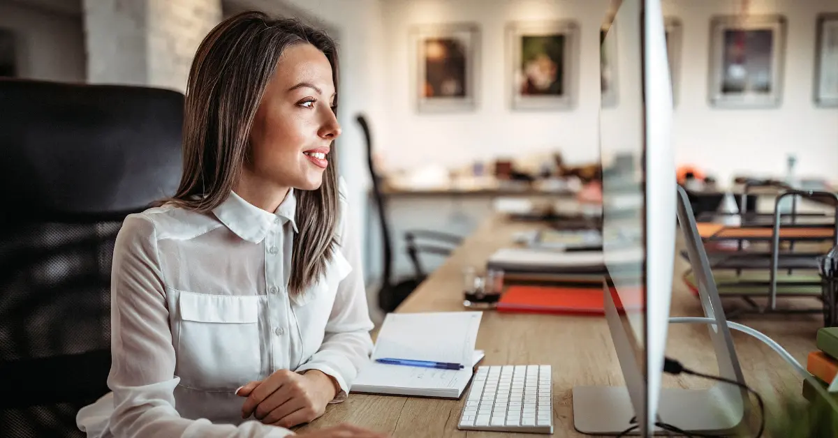 Woman in a modern workspace using her computer; researching about a self-employed tax calculator.