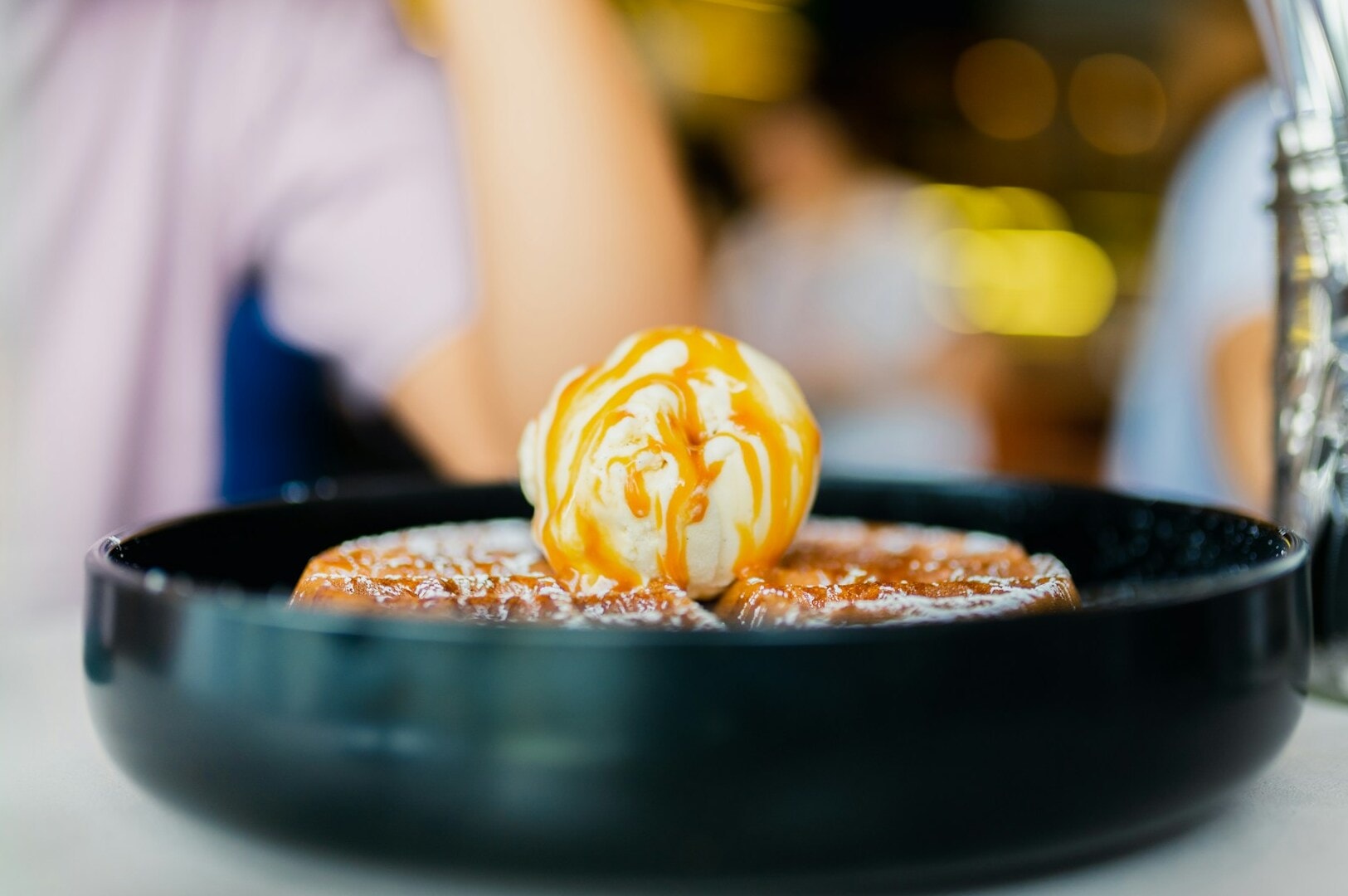 A plate of dessert on a table with a person sitting nearby, highlighting a trending dish from Singapore's culinary culture.