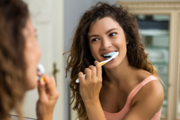 a woman gently brushing her teeth