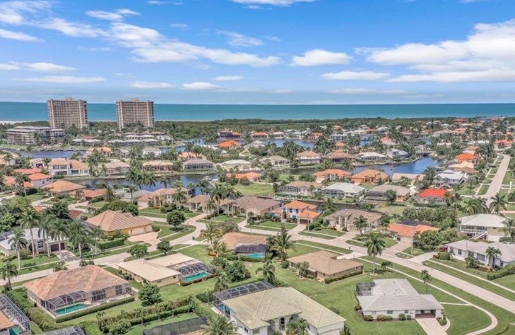 The image depicts a serene canal with vibrant blue water, surrounded by lush greenery typical of the Tigertail Beach area on Marco Island. This picturesque scene captures the essence of the ultimate island lifestyle, showcasing the tranquil beauty of waterfront living in this prestigious neighborhood.